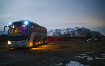 Tour coach parked at dusk near mountains