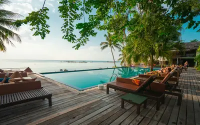 Wooden deck with loungers beside a pool and the sea