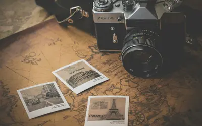 Vintage camera on a travel map with printed photos